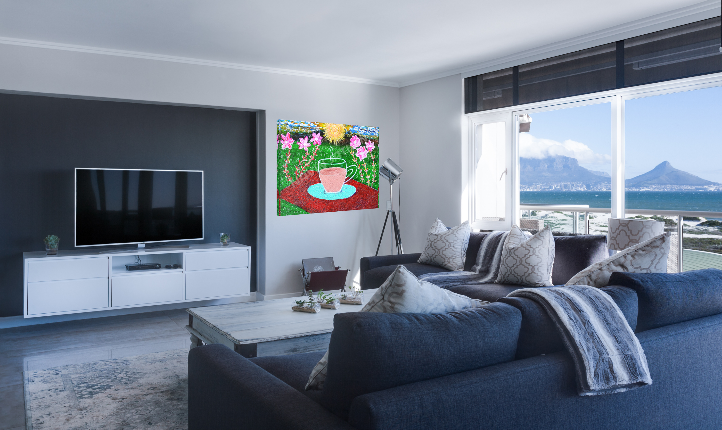 Modern living room with a blue sofa, TV, and large window with a scenic view.