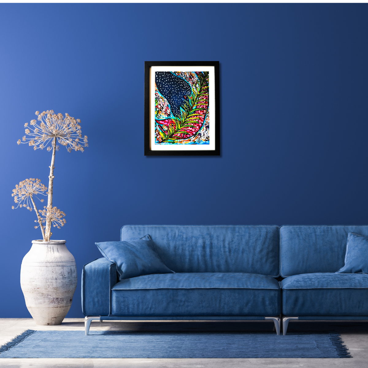 Living room with blue sofa, decorative plant, and framed artwork on a blue wall.