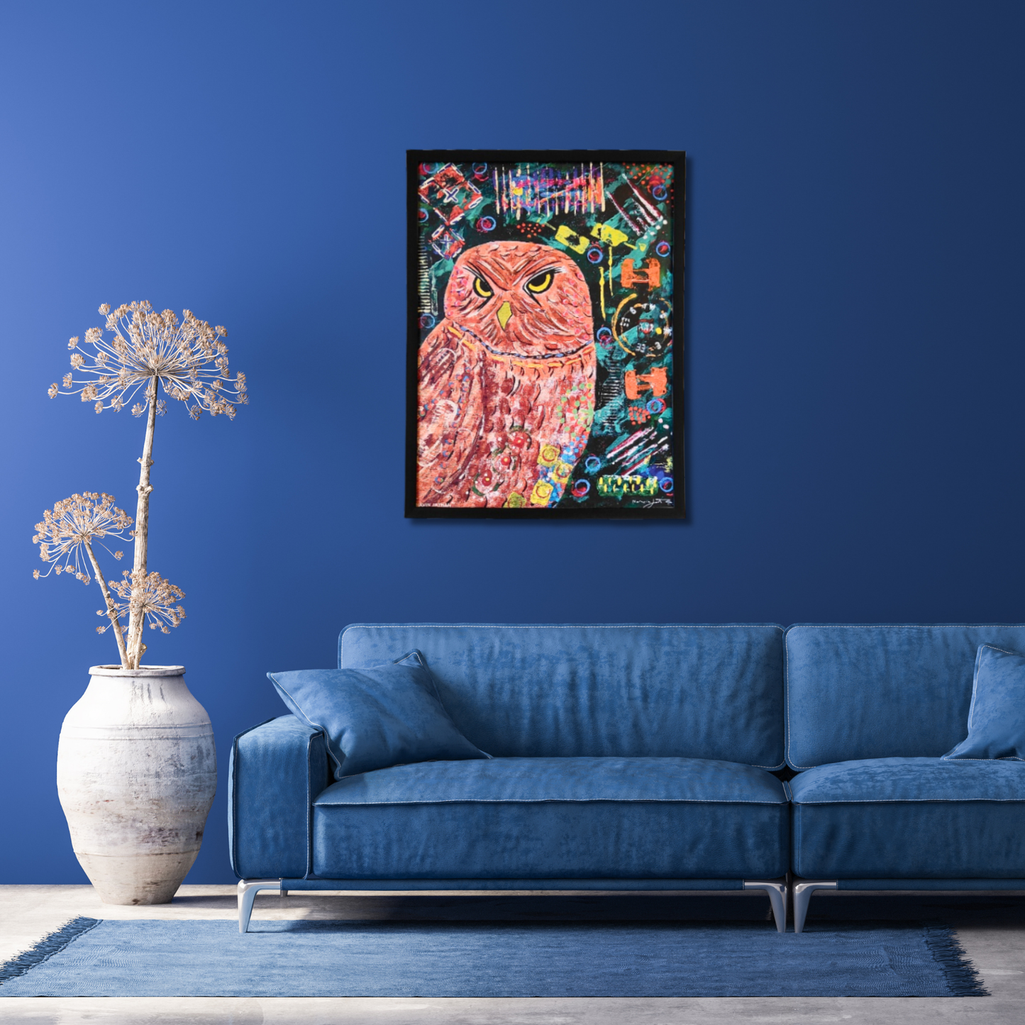 Colorful owl painting on a blue wall above a blue sofa with a decorative figures beside it.